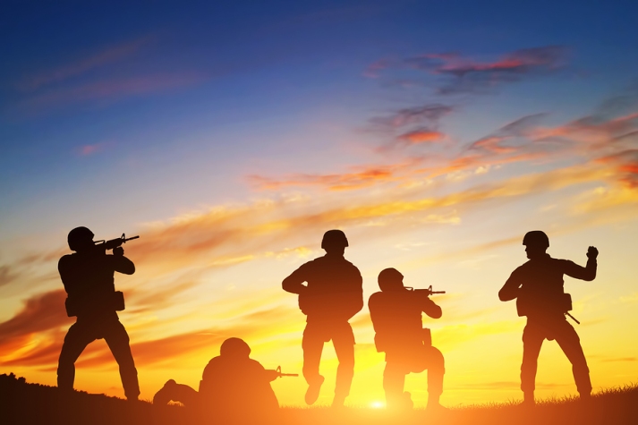 Soldiers in assault shooting with weapon, rifle at sunset. War, army, military.